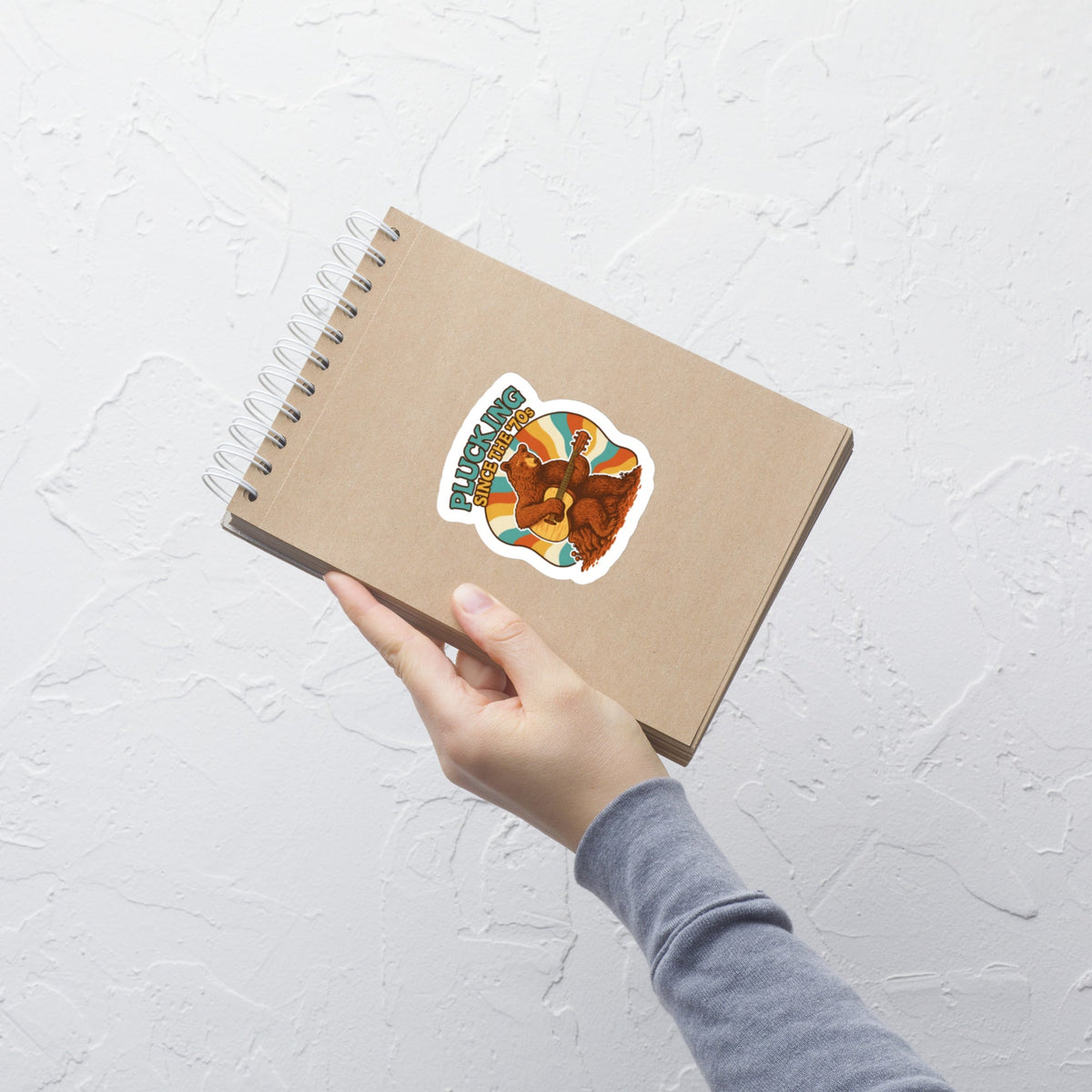 Groovy Bear Acoustic Guitar Music Sticker on a notebook held by hand