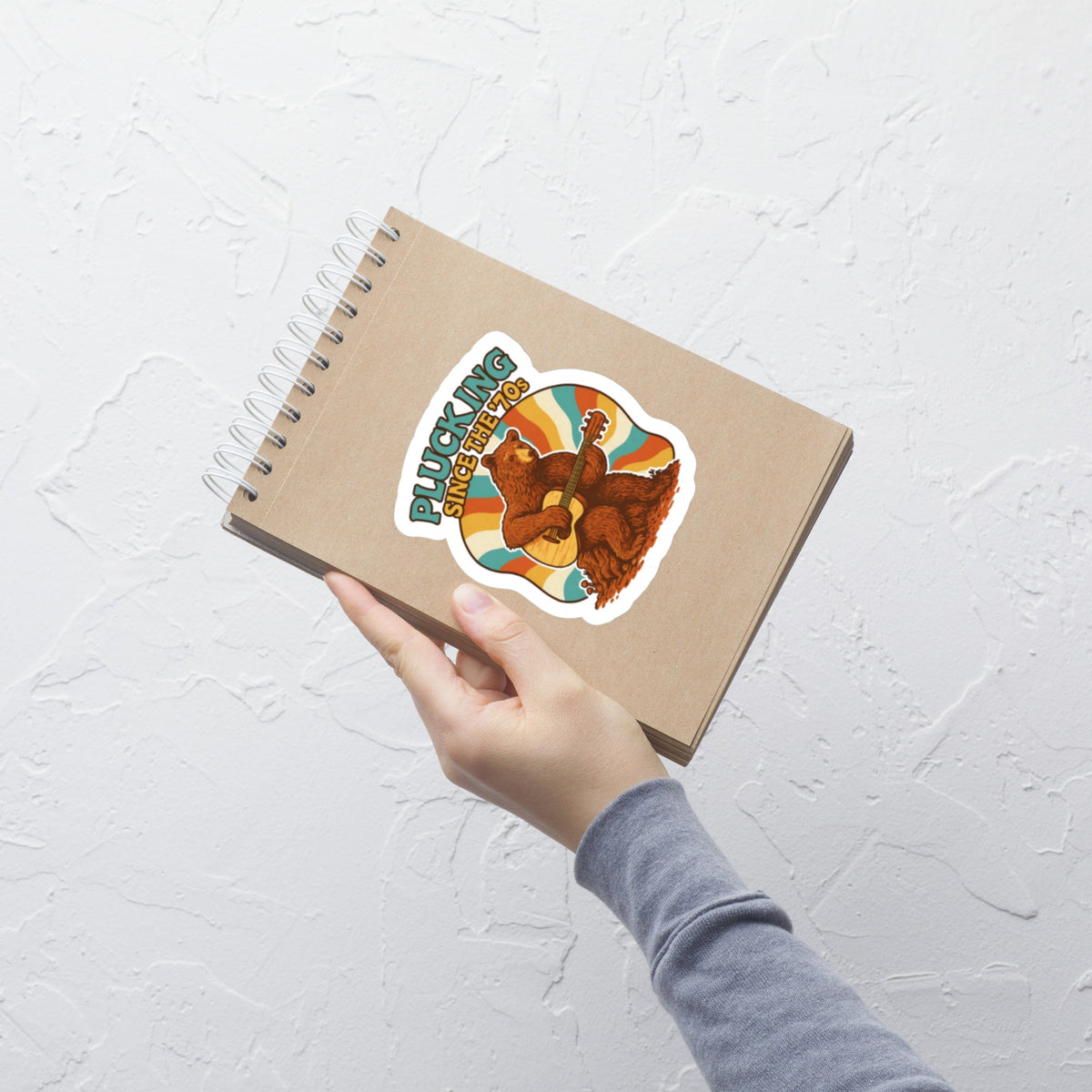 Groovy Bear Acoustic Guitar Music Sticker on a notebook held by hand